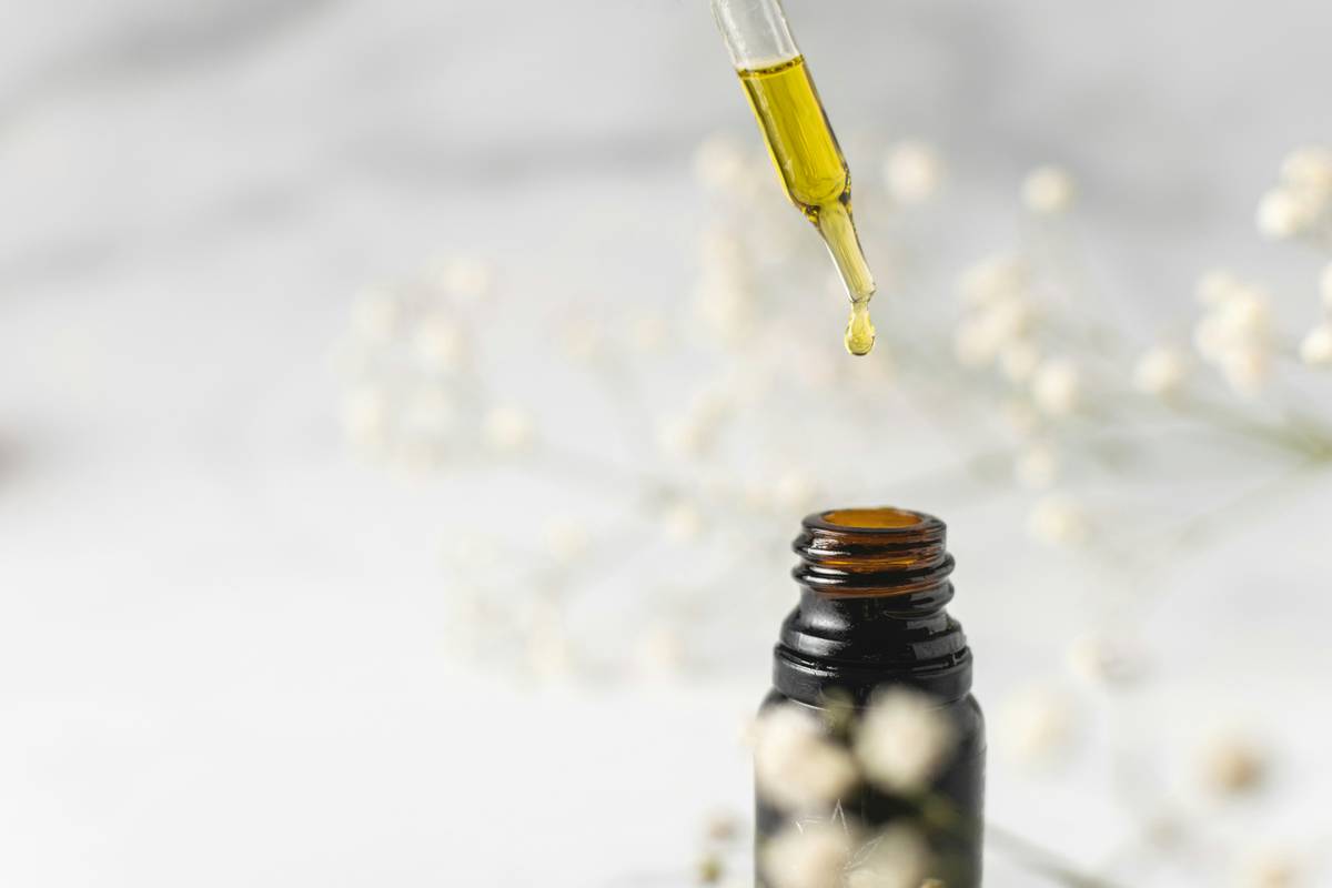 Woman applying vital body facial oil to glowing skin at night