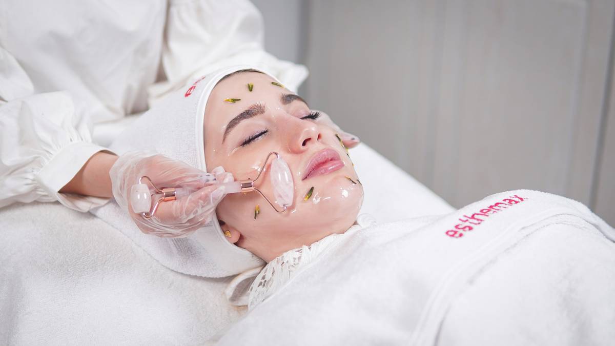 Woman applying face oil that repairs skin on damp cheeks at night