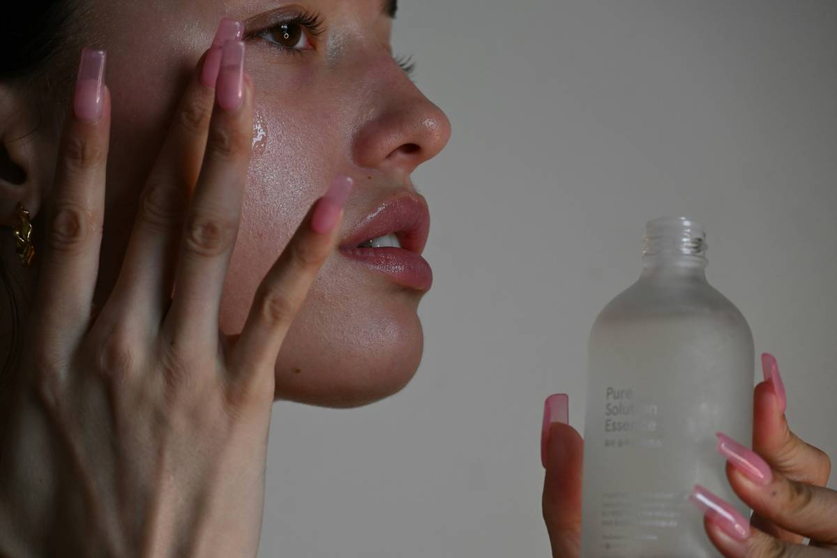 Woman applying bio oil skincare oil to damp face at night for optimal absorption